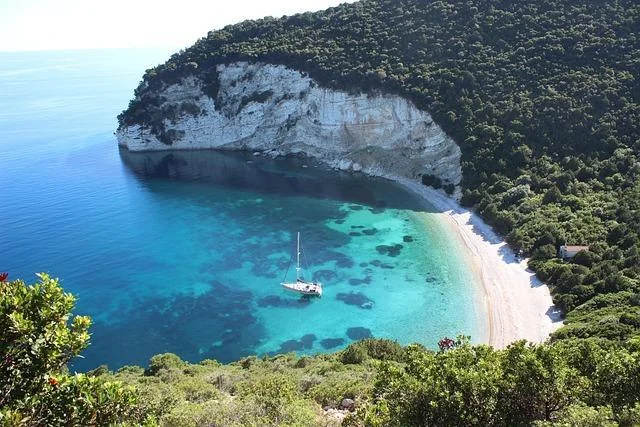 A yacht anchored in the turquoise water of a secluded Ionian bay