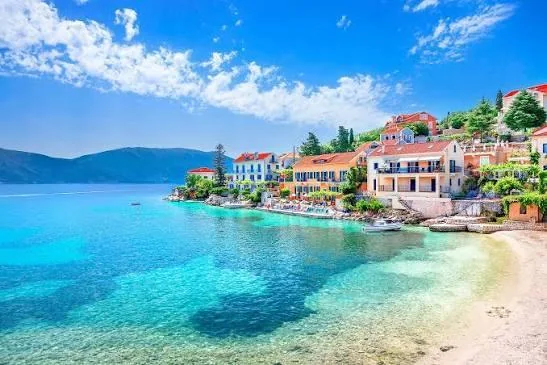 Sailing yacht approaching a green Ionian island village
